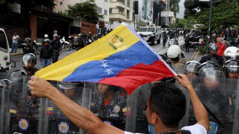 An anti-Maduro demonstrator waves a Venezuelan flag in front of the Venezuelan National Police officers during a demonstration against the government of Nicolás Maduro organized by supporters of Juan Guaidó on March 10, 2020, in Caracas, Venezuela. (Edilzon Gamez/Getty Images)