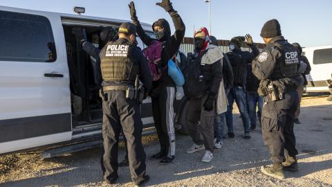 A United States Customs and Border Protection officer searches immigrants before transporting them from the US-Mexico border on December 8, 2023, in Lukeville, Arizona. (John Moore via Getty Images)