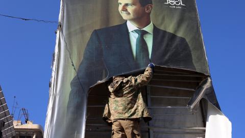 An anti-government fighter tears down a picture of Syrian President Bashar al-Assad in Aleppo, Syria, on November 30. (Mohammed al-Rifai via Getty Images)