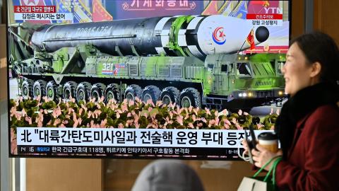 A woman walks past a television screen showing a news broadcast of a North Korean military parade showcasing a record number of nuclear and intercontinental ballistic missiles in Seoul on February 9, 2023. (Jung Yeon-je/AFP via Getty Images)