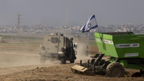 An Israeli army vehicle passes by an Israeli tractor working along the border with the Gaza Strip on January 16, 2025, in Israel. (Amir Levy via Getty Images)