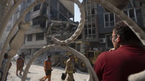 Iranian workers walk past a destroyed residential building due to Israeli attacks in Tehran, Iran, on June 13, 2025. (Photo by Morteza Nikoubazl/NurPhoto via Getty Images)