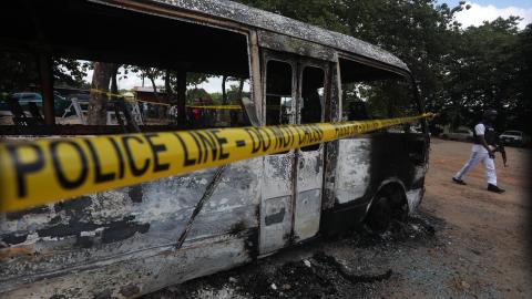 A police officer walks beside a burnt prison vehicle in Abuja, Nigeria, on July 6, 2022, after suspected Boko Haram gunmen attacked the Kuje Medium Prison. (Kola Sulaimon via Getty Images)