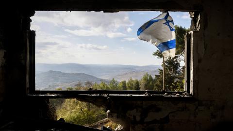 An Israeli flag flutters on the window of a building that was damaged during the war between Israel and Hezbollah in Kibbutz Menara in northern Israel on November 28, 2024. The Israeli military on November 28 said it hit a facility in southern Lebanon belonging to Iran-backed militant group Hezbollah, a day after a ceasefire between the group and Israel began. (Photo by Jalaa MAREY / AFP) (Photo by JALAA MAREY/AFP via Getty Images)
