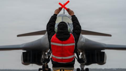 A U.S. Air Force B-1B Lancer crew chief marshals a B-1 after returning from a CONUS-to-CONUS mission in support of Operation Epic Fury, March 4, 2026. The B-1B is a long-range, multi-role bomber that carries the largest payload of precision guided and unguided munitions in the Air Force inventory. (U.S. Air Force photo)