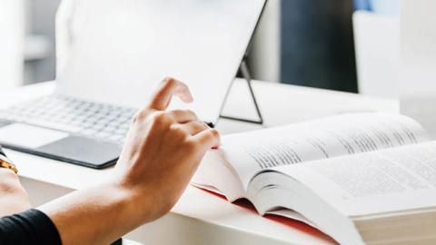 A student references a textbook while attending a university seminar. (Getty Images)