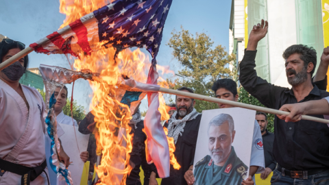 Iranian protesters burn US and Israeli flags next to a portrait of Major General Qasem Soleimani during an anti-Israel protest in downtown Tehran on August 9, 2022. (Morteza Nikoubazl/NurPhoto via Getty Images)