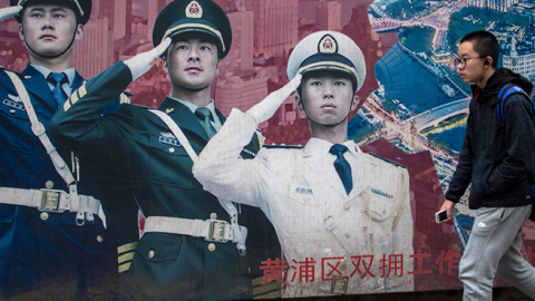 A man passes a military propaganda poster in Shanghai on March 5, 2017. (JOHANNES EISELE/AFP/Getty Images)