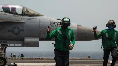 Sailors signal that an F/A-18E Super Hornet fighter jet is ready for takeoff on the flight deck of aircraft carrier USS Ronald Reagan. (U.S. Navy)