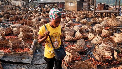 A woman walks among baskets full of tomatoes vandalized after deadly ethnic clashes between the northern Fulani and southern Yoruba traders at Shasha Market in Ibadan, southwest Nigeria, on February 15, 2021. (Pius Utomi Ekpei/AFP via Getty Images)