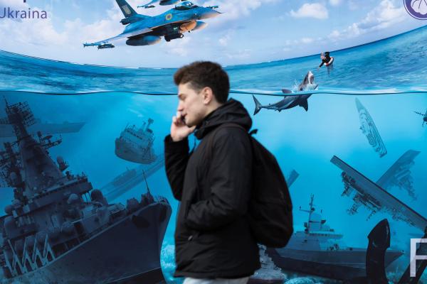 People walk past a poster depicting Russian warships sunk by Ukrainian attacks in the Black Sea on March 16, 2024, in Kyiv, Ukraine. (Photo by Oleksii Chumachenko/Global Images Ukraine via Getty Images)