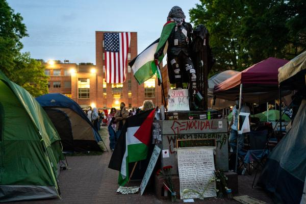 An American flag hangs from the roof of Lisner Hall of the George Washington University Law School as people walk around an encampment at University Yard on May 3, 2024 in Washington, DC. Pro-Palestinian encampments have sprung up at college campuses around the country with some demonstrators calling for schools to divest from Israeli interests amid the ongoing war in Gaza. (Photo by Kent Nishimura/Getty Images)