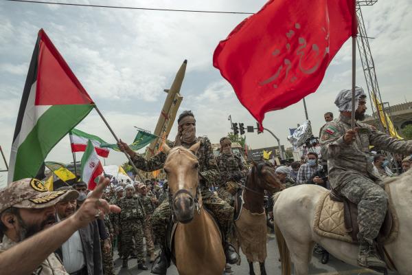 An Islamic Revolutionary Guard Corps member carrying a Palestinian flag in downtown Tehran on April 29, 2022. (Morteza Nikoubazl/NurPhoto via Getty Images)