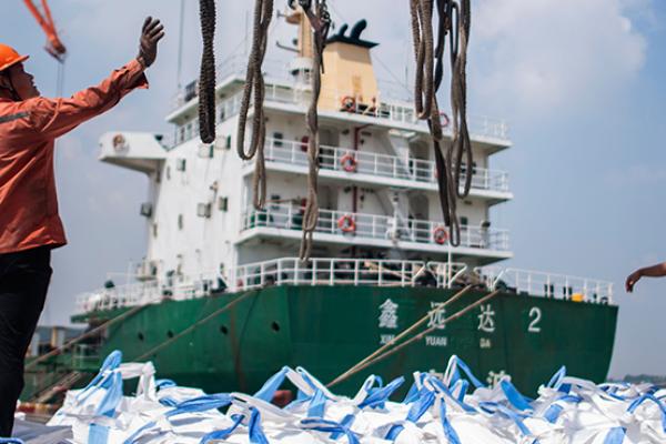 Workers unloading bags of chemicals at a port in Zhangjiagang in China's eastern Jiangsu province, August 7, 2018