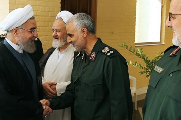 Iranian President Hassan Rouhani (L-2) shakes hands with Iranian Quds Force commander Qassem Soleimani (R-2) during the 21st Nationwide Assembly of the Islamic Revolution Guard. (Pool/Iranian Presidency Press Office/Anadolu Agency/Getty Images)