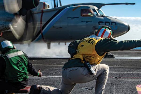 Lt. Lisa Amble signals to the pilot of an E-2D Hawkeye before launching from the flight deck of the Nimitz-class aircraft carrier USS Harry S. Truman (CVN 75), Feb. 21, 2022. (U.S. Navy photo)