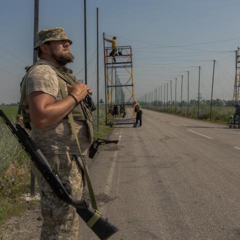 A Ukrainian serviceman stands guard with a shotgun as his fellow soldiers install anti-drone nets over a road at an undisclosed location in the eastern Donetsk region on July 8, 2025, amid the Russian invasion of Ukraine. (Roman Pilipey via Getty Images)