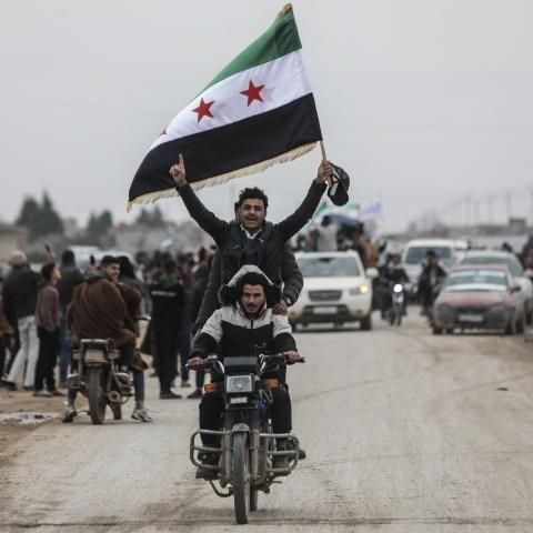 Men riding a motorbike wave a Syrian flag as Syrian government forces enter the Kurdish-majority city of Qamishli on February 3, 2026. (Getty Images)