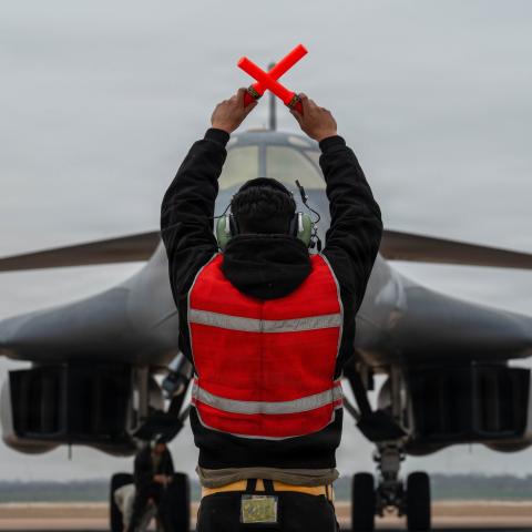 A U.S. Air Force B-1B Lancer crew chief marshals a B-1 after returning from a CONUS-to-CONUS mission in support of Operation Epic Fury, March 4, 2026. The B-1B is a long-range, multi-role bomber that carries the largest payload of precision guided and unguided munitions in the Air Force inventory. (U.S. Air Force photo)